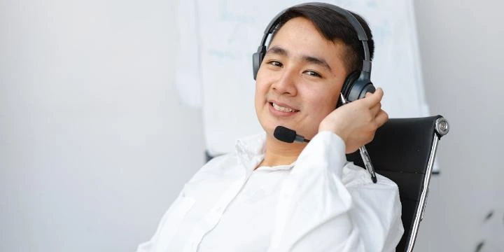 Atendente usando headset, feliz por estar recebendo uma avaliação online, simbolizando a importância da resposta para avaliações e feedbacks.
