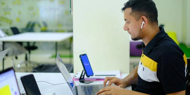 Desenvolvedor usando notebook e smartphone em um ambiente de trabalho, criando um site mobile-friendly responsivo e moderno.